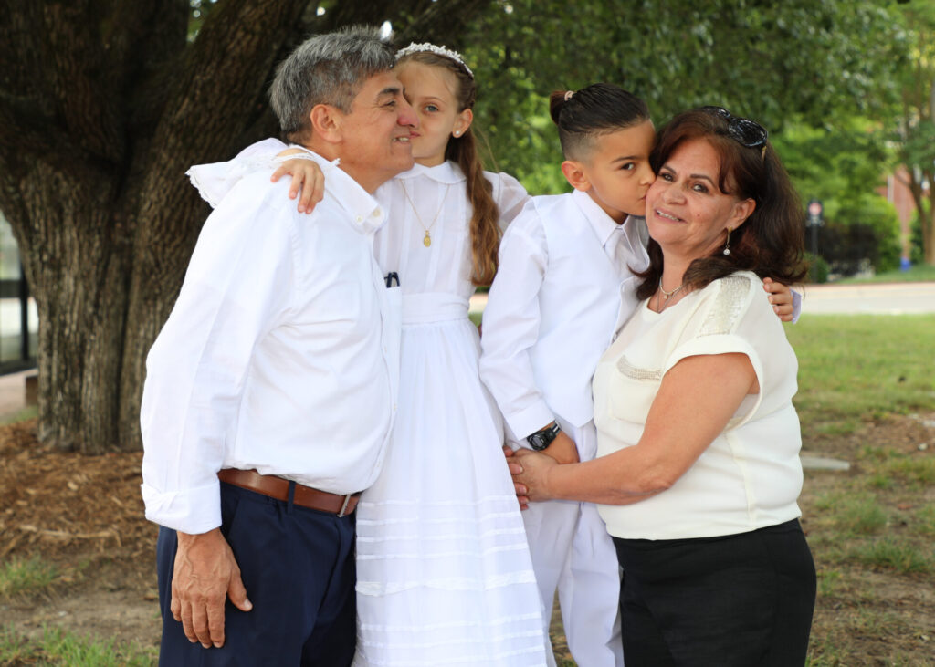 Two children making their First Communion kiss grandma and grandpa at the Newman Center near Chapel Hill, NC.